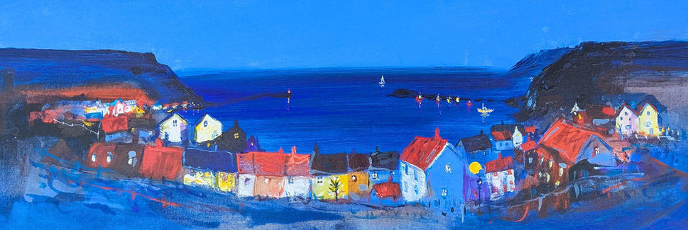 A dramatic nocturnal view of Staithes Village with the brightly illuminated houses contrasting against the deep blues of the sea and cliffs.