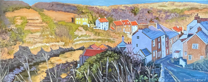 A panoramic view looking down Staithes High Street bathed in the golden glow of the sinking winter sun.