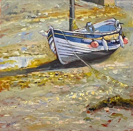 A view of a blue and white fishing boat resting on river bed at low tide.