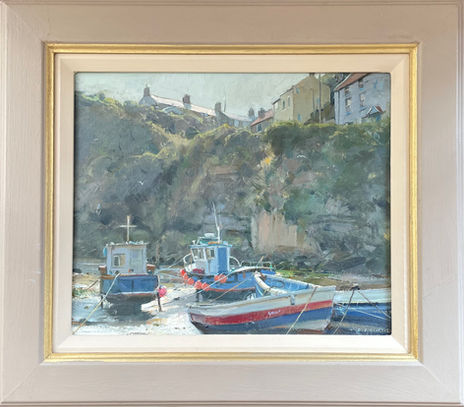 A close cropped scene dominated by tall sandstone cliffs and Cowbar cottages. Traditional wooden fishing boats are moored in the foreground.