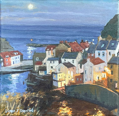 A glowing full moon is reflected in the sea and Staithes Beck whilst a huddle of cottages are illuminated by streetlamps.