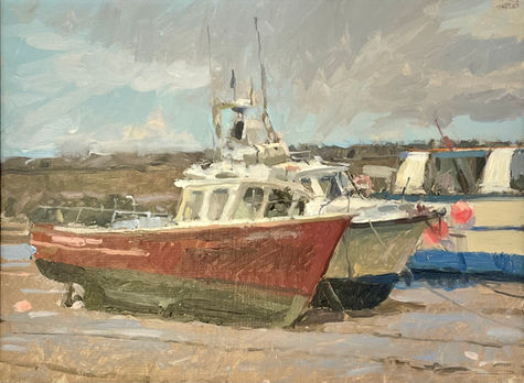 A tranquil scene of modern fishing boats resting on the sand in Staithes Harbour.