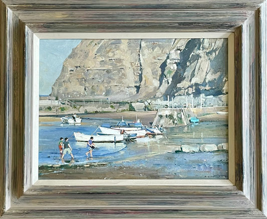 Visitors enjoy paddling around the moored boats in Staithes Harbour on a sunny day.