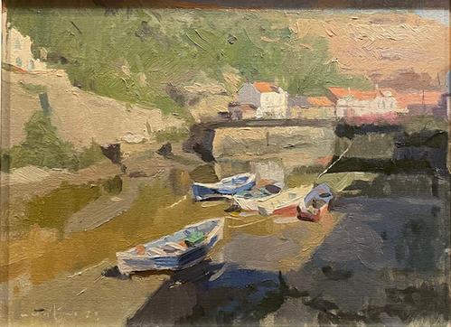 An impressionist view from the side of Staithes Beck looking towards the footbridge on a sunny day- some fishing boats in the foreground.