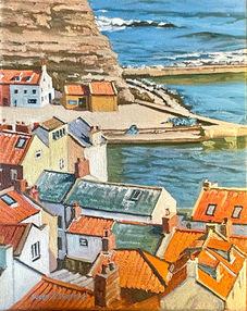 A vibrant view of Staithes cottages whose terracotta rooftops glow against the blue harbour water beyond.