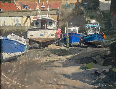 Wooden and commercial boats lie on the dry bed of Staithes Beck in the sunshine.