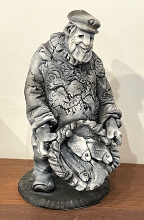 A cheerful fisherman wearing a traditional gansey proudly displays his basket of fish.