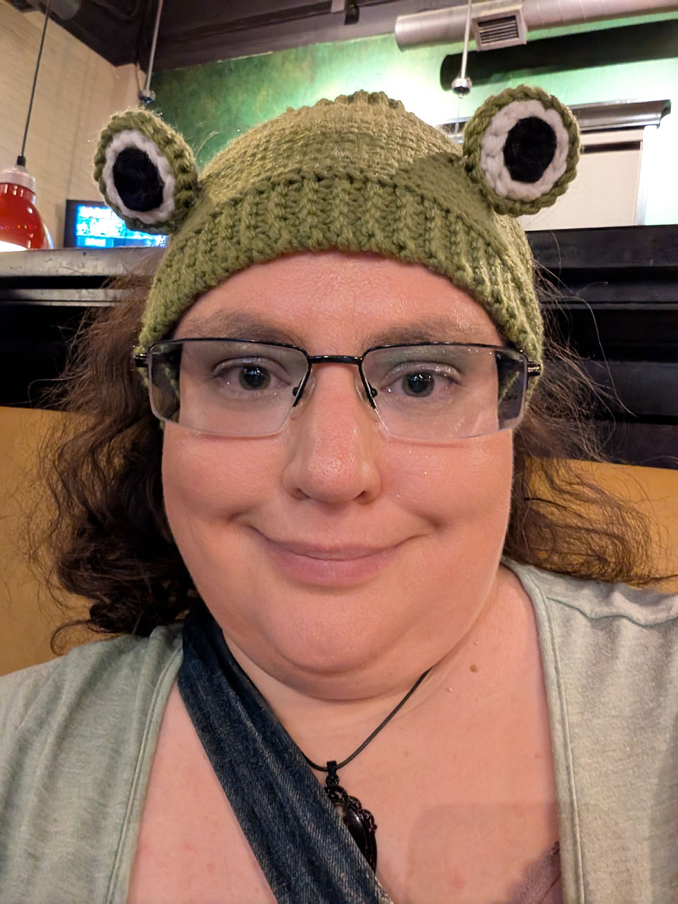 A fat chick with a dumb smile taking a selfie.  She is wearing a knitted frog hat.