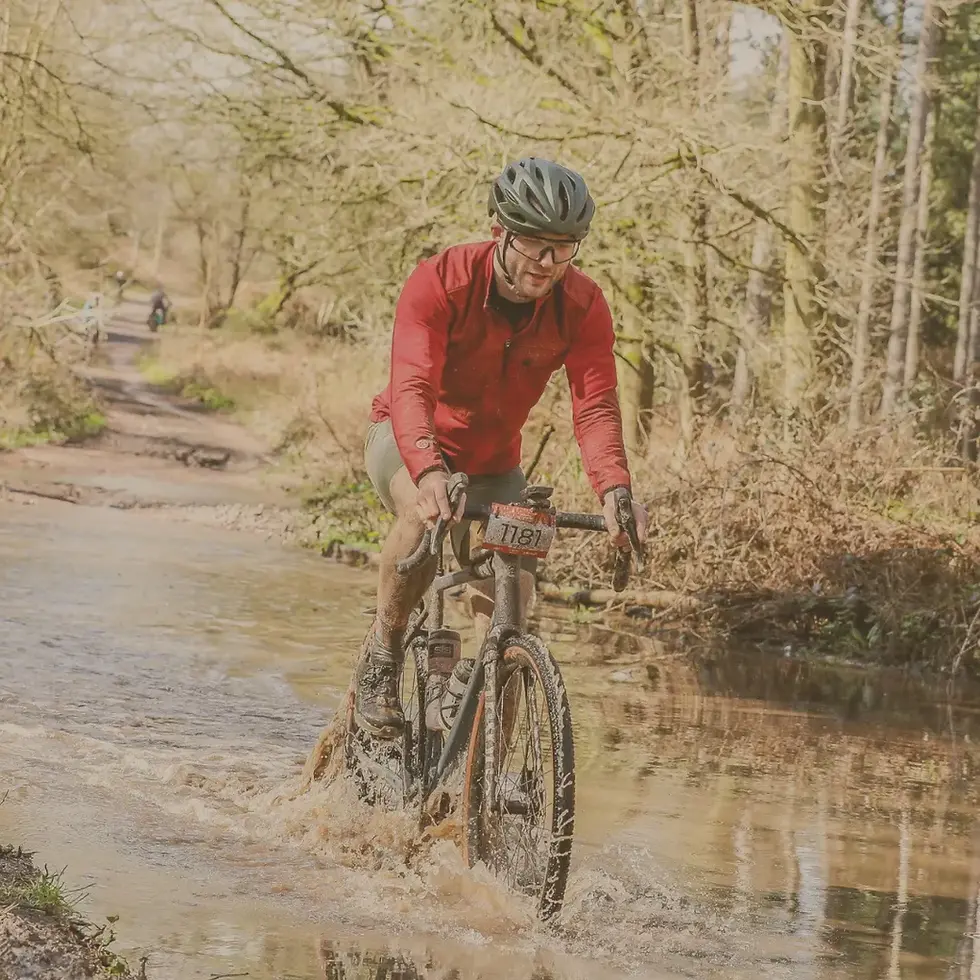 Man riding a gravel bike through water.