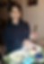 Photo of 20 year old Shruti smiling sitting at a dining table, eating a dinner of a small piece of fish and some cauliflower soup.