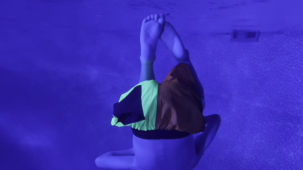 Thumbnail: A child somersaulting upside and backwards underwater in blue pool, wearing SwimHumyn's UPF Sun Protective Kid's Board Shorts