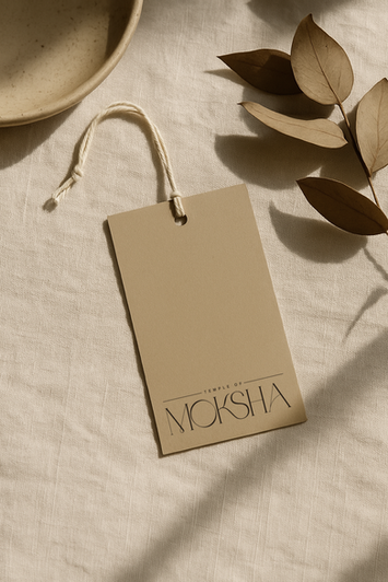 Beige hang tag with Temple of Moksha logo, styled on linen with warm shadows and foliage.