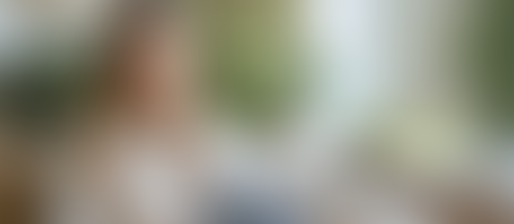 Noor naine otsib arvutist infot, istudes mugavas valgusküllases ruumis, taustal taimed ja raamatud