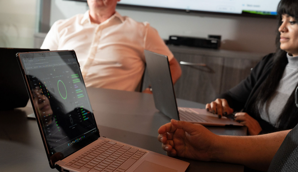 Team members working on their laptops in a meeting, discussing the importance of AI in business.