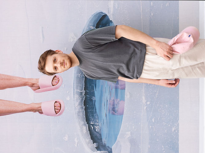 Tilman in beigen Hosen und rosa Pantoffeln vor Wandgemälde