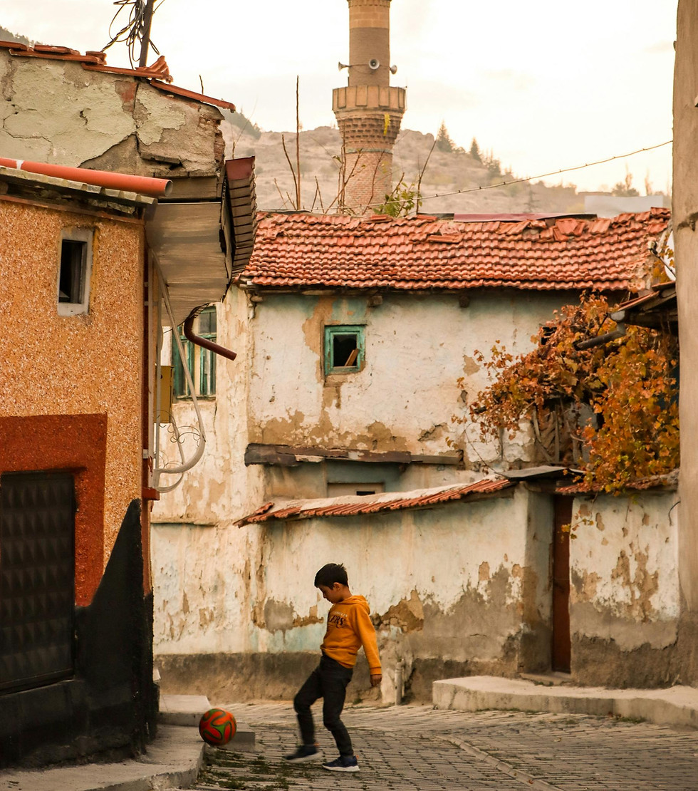 Young boy playing soccer in a rustic village brand story.