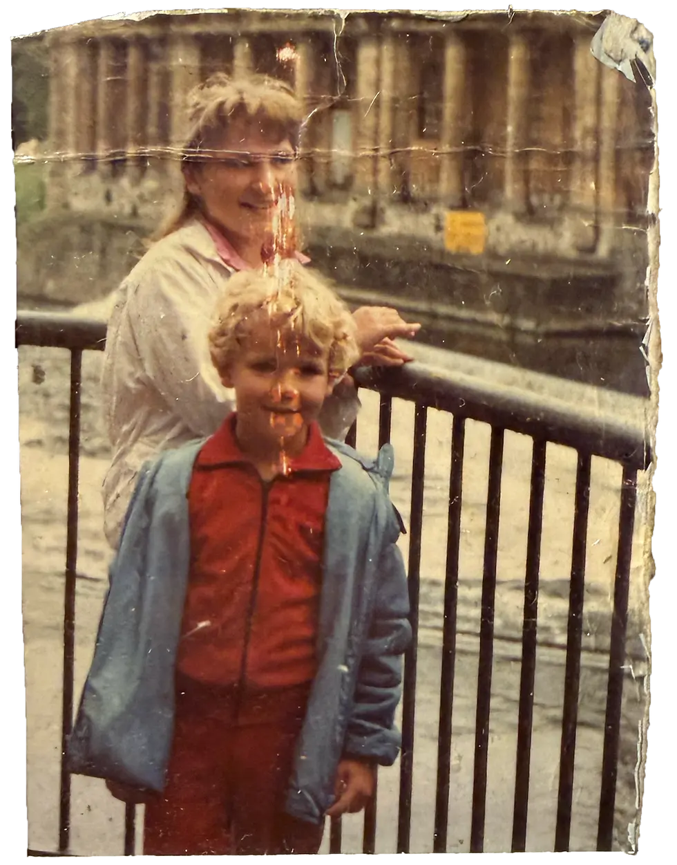 Woman and child posing by a railing, building background about the location.