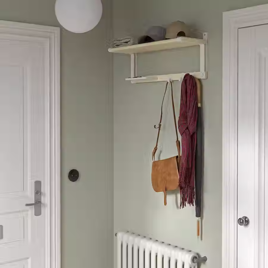 Studio apartment entryway with wall-mounted shelf and hooks for coats and bags.