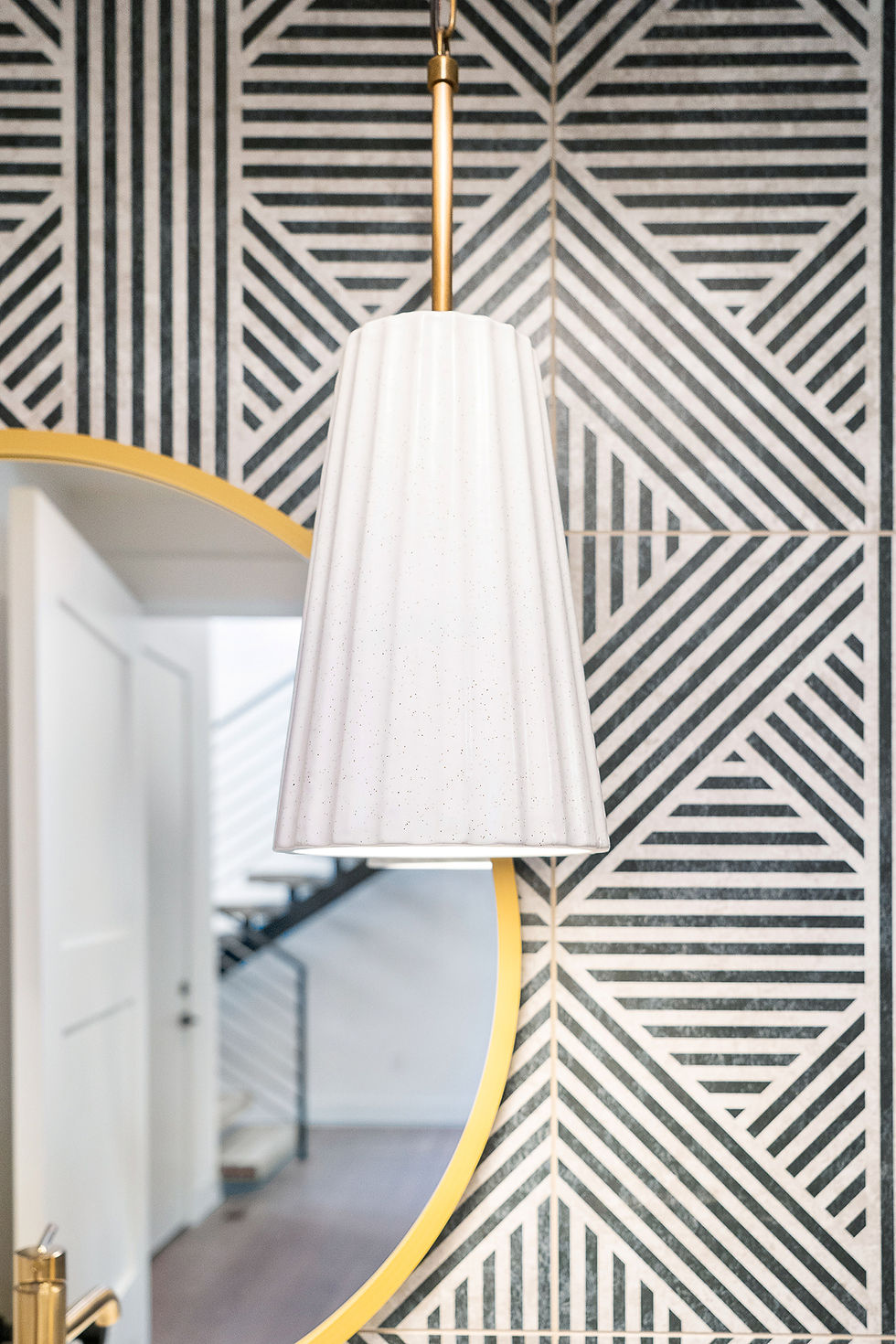 Project 3735 black and white geometrically striped walls with gold mirror and white shaded lamp