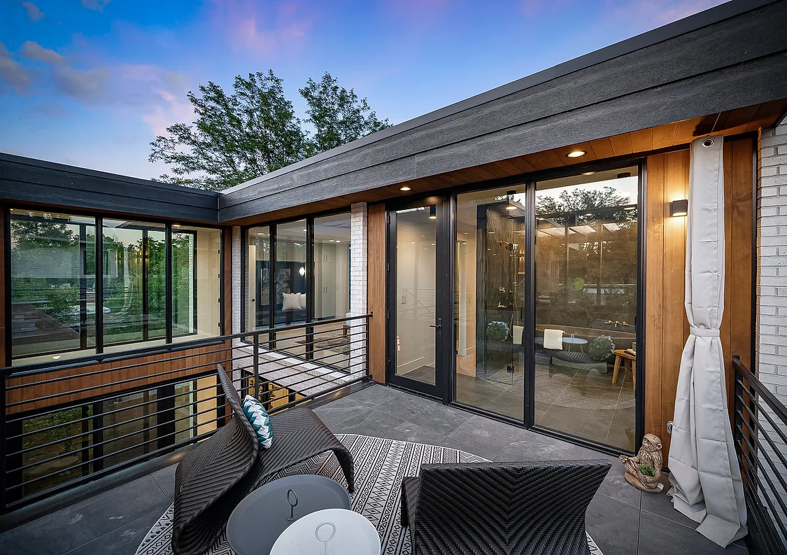 The upper patio opens to interior spaces through full-height windows, extending the living experience outdoors.