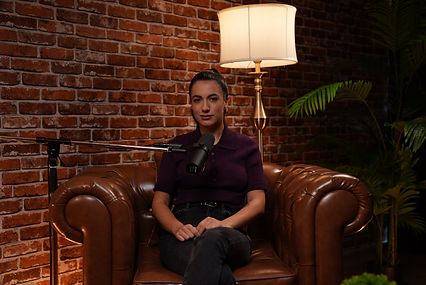 Female podcaster on brown leather sofa with brick wall at Dubai podcast studio podcast studio Dubai