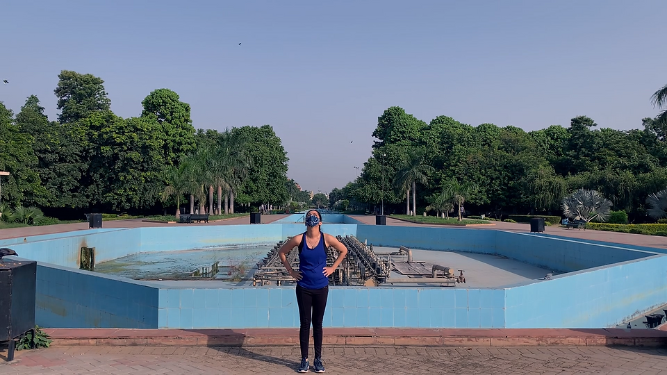 In a solitary park a woman wearing a mask is holding her waist while looking up