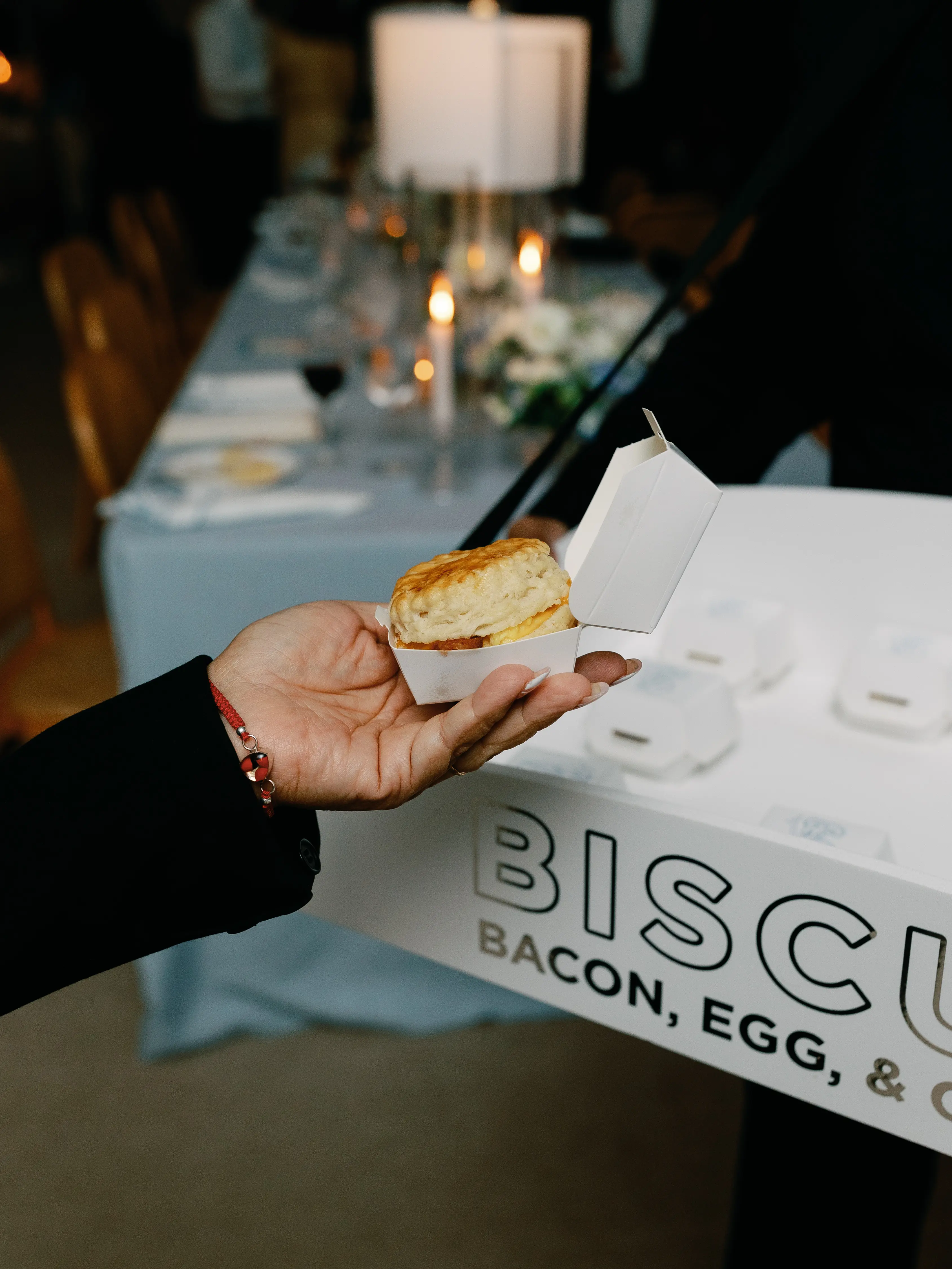 person taking a breakfast biscuit from a tray