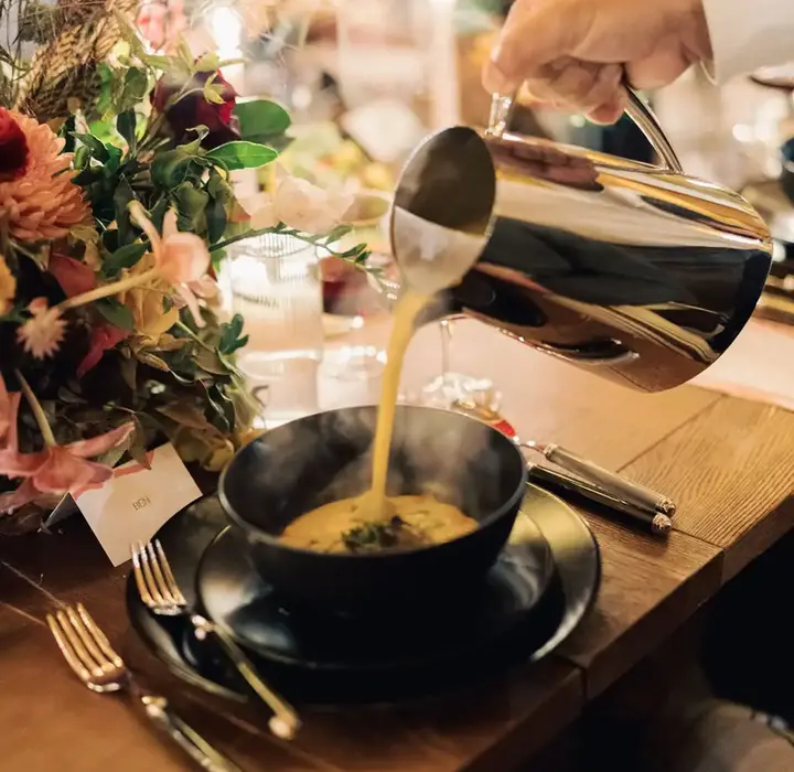 Server pouring soup into guest's bowl