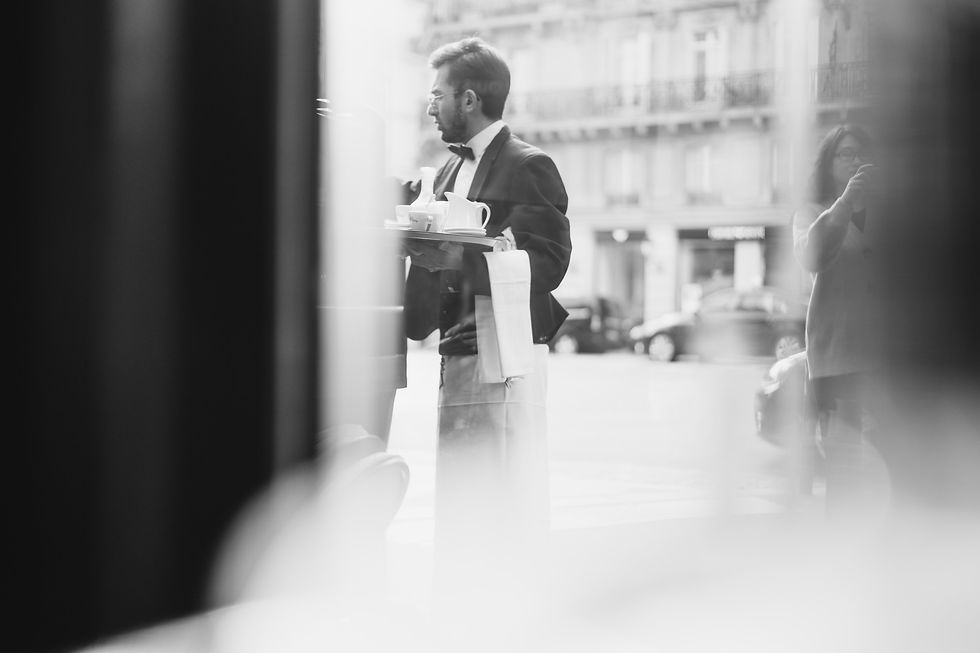 A photograph of a waiter in a bow tie holding a tray of drinks