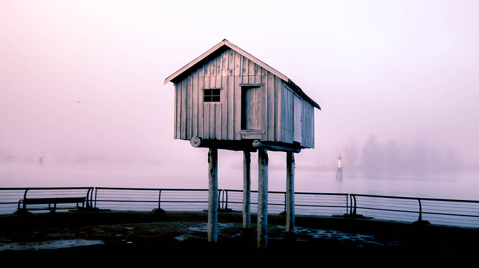 Photograph of a wooden cabin on stilts next to a lake