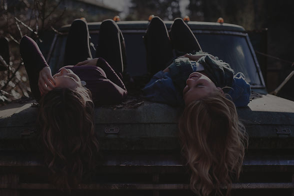 two girls sitting on a truck talking