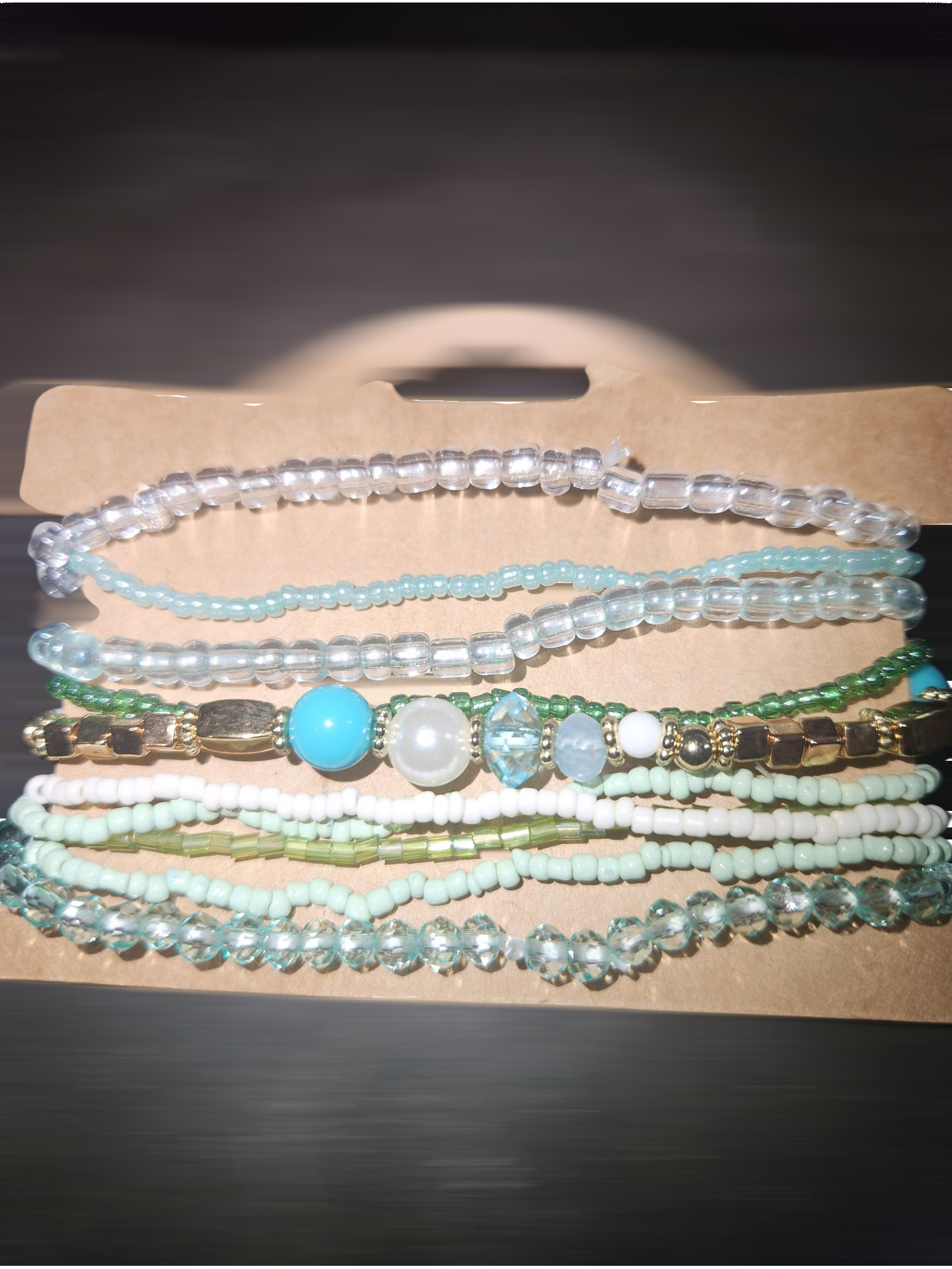Stacked beaded bracelets in shades of green and blue on brown background.