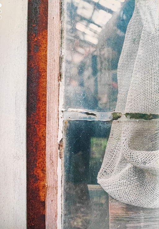 Fenêtre ancienne avec rideau et reflet sur la vitre – photographie d’Hélène Bernard.