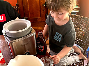 Small boy making ice cream with an ice cream maker.