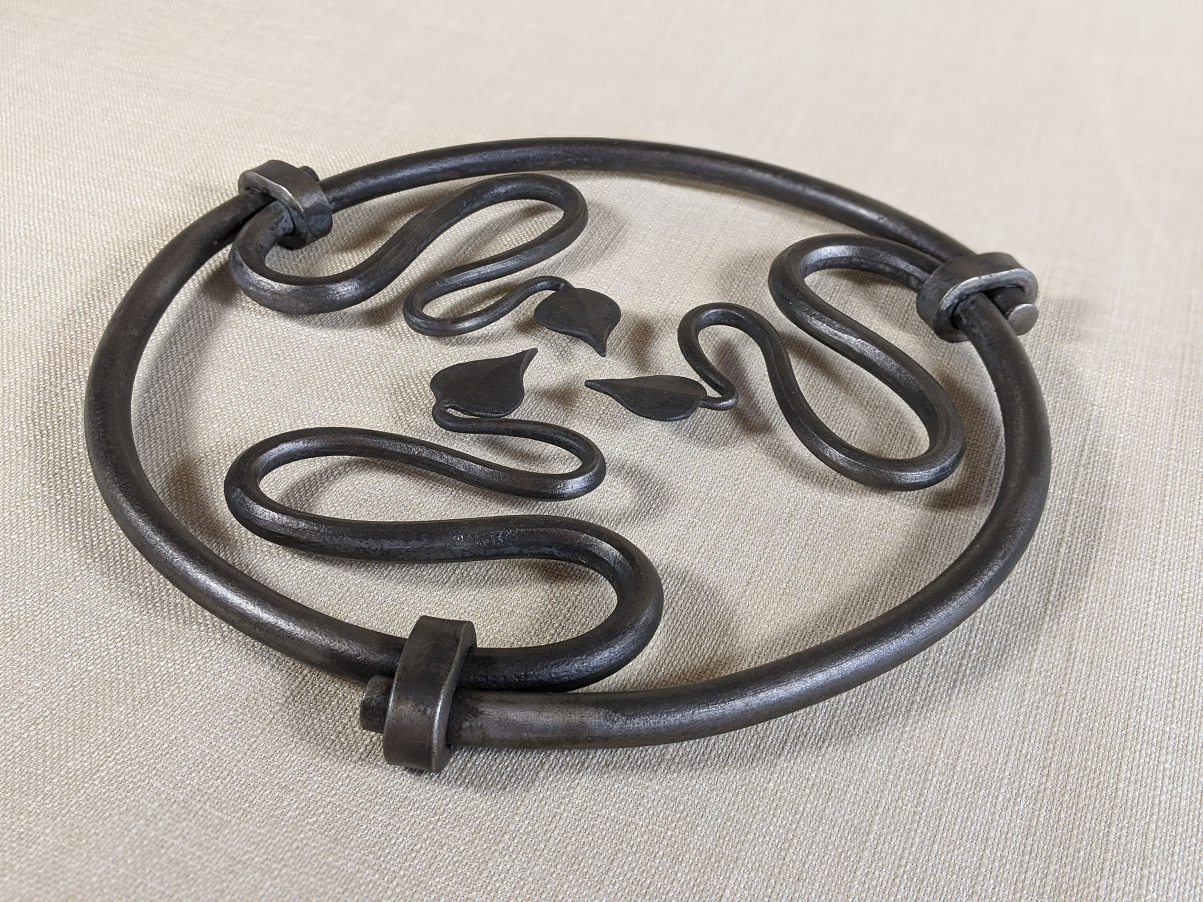 A hand forged kitchen Pot Trivet featuring a leaf design, handmade by Tom Fell - Blacksmith