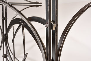 Detail of a forged steel dining table showing hammer marks and riveted sections