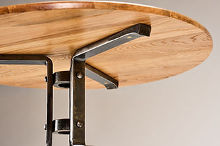 Three forged steel legs joining a central column beneath the table top