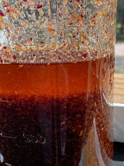 an infused oil settling in a mason jar on a windowsill