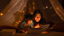 a parent and child read a book under twinkle lights