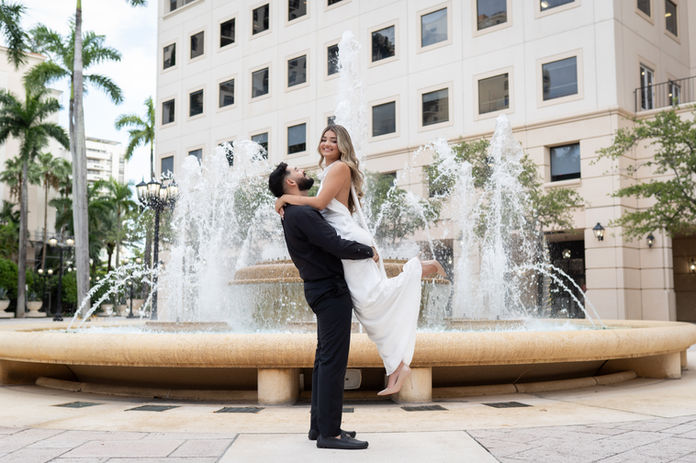 Bride and groom dancing by fountain during Miami engagement session with HG Photo Films