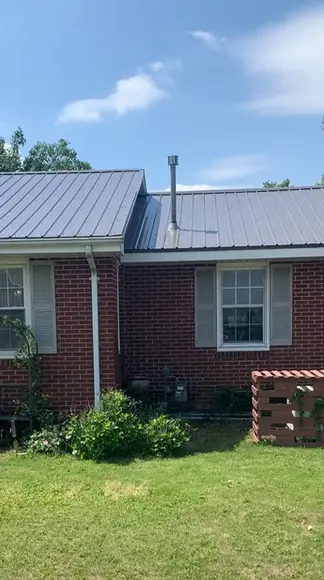 Ranch-style home with light gray metal roofing panels and matching gutters