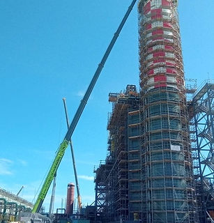 Obra de grande escala com guindaste Zoomlion ZTC1000V753 posicionado próximo a torre em estrutura metálica.