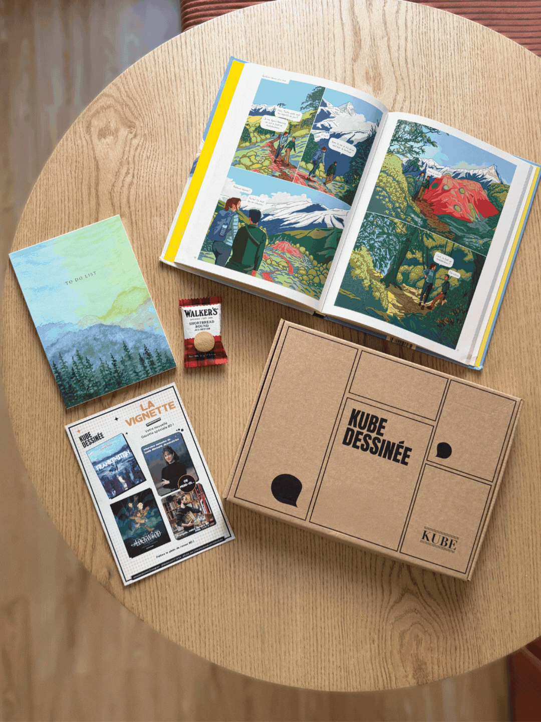 Box BD Kube Dessinée ouverte sur une table en bois, abonnement BD adulte par libraire indépendant
