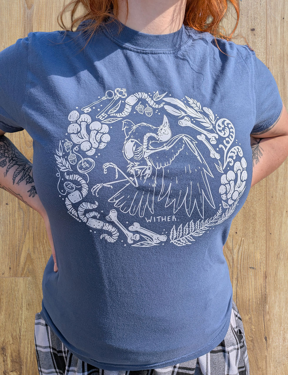 A femme person wears a shirt featuring a crow skeleton surrounded by nature. It reads, "Wither."