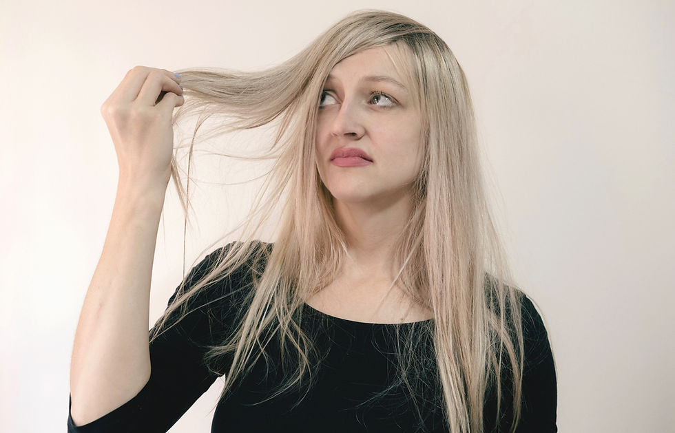 Herbs for Hair Growth and Thickness: woman with dull, lifeless hair looking at her hair in dismay