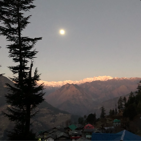 A breathtaking, wide-angle view of the majestic snow-capped Himalayan mountain peaks rising above a lush valley in Nagarkot, Nepal.