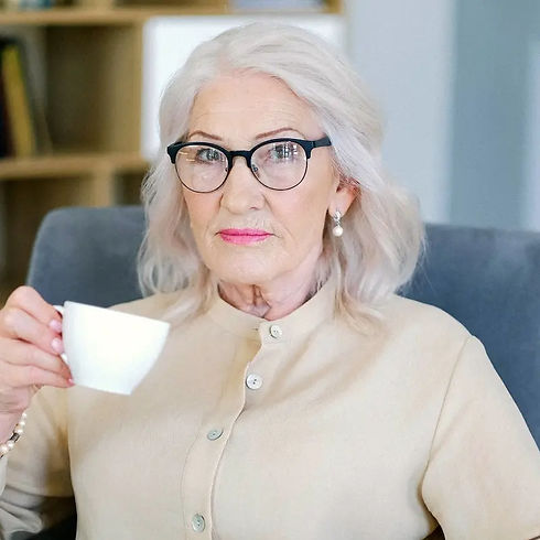 A mature woman enjoying a peaceful moment with a warm beverage, illustrating rhythmic living and self-paced Ayurvedic study.