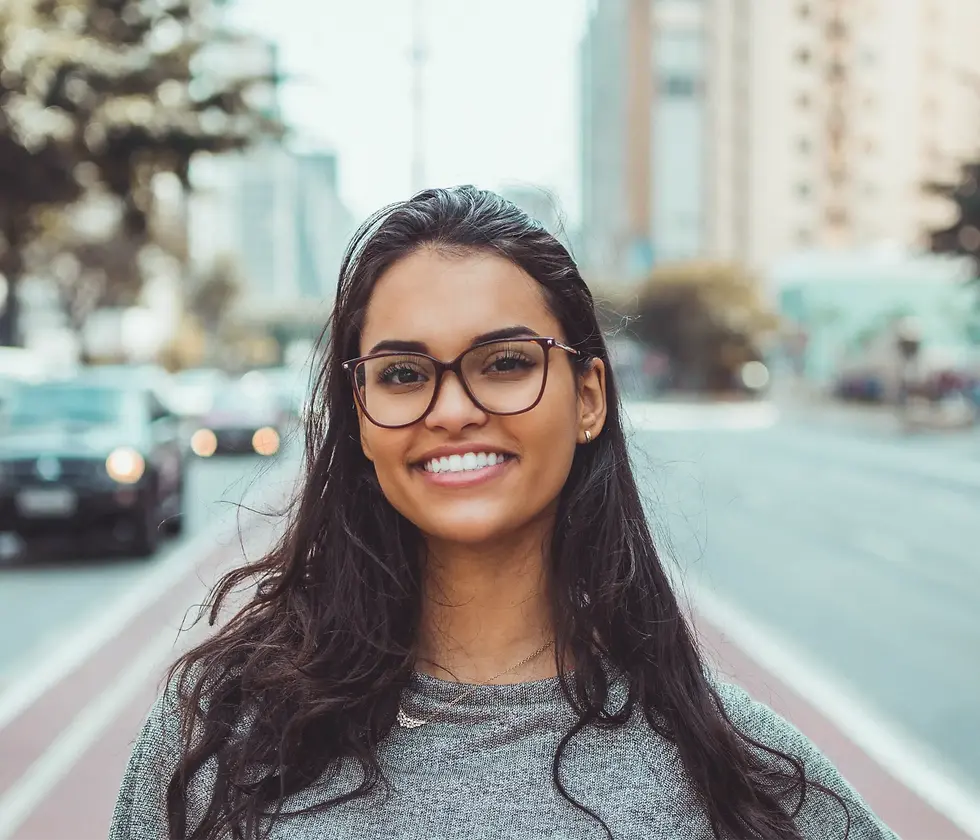 smiling woman with long hair wearing glasses standing on the street