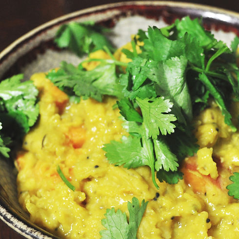 A nourishing bowl of Ayurvedic Kitchari with fresh herbs, representing healing foods for women over 40.