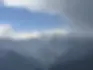 A serene, circular view looking out at the massive, snow-capped peaks of the Kanchenjunga mountain range on a cool, overcast day in Gangtok, Sikkim.